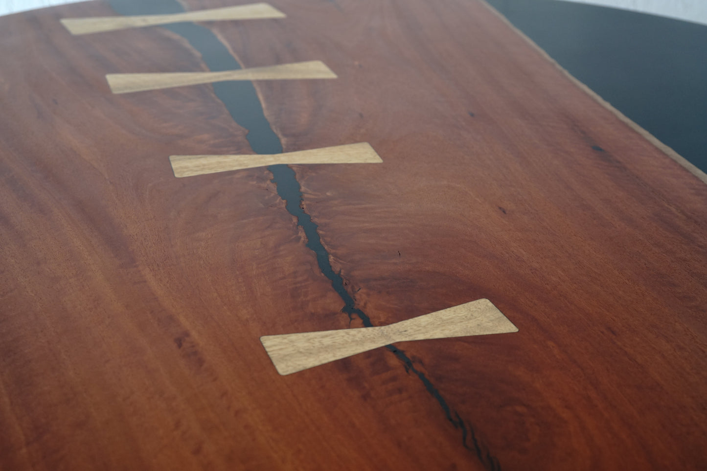 Close-up of a Timber Grooves Jarrah Tuxedo Coffee Table with visible marri bowties along a natural split in the wood. The table features a smooth, polished surface with rich wood grain patterns, accentuated by subtle streaks of black resin.