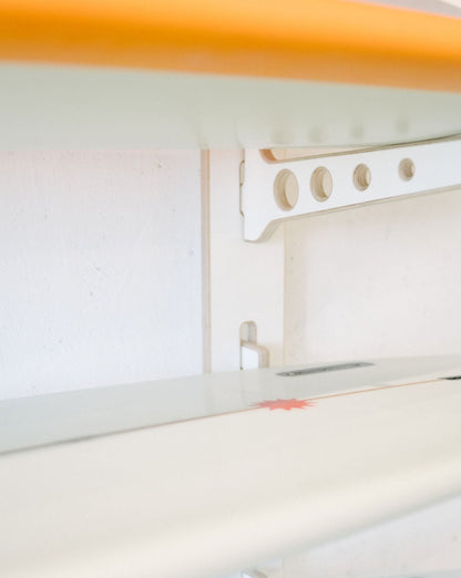 A close-up view of the Surfboard Rack Wall Mount by Timber Grooves, showcasing white surfboards neatly arranged, with one board featuring a red star design.